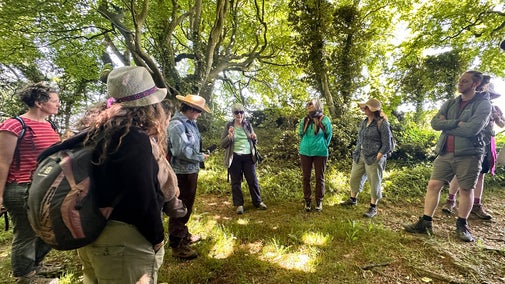 A group of people listen to a talk at Newmarket Plantation on the Stopping Places Walk